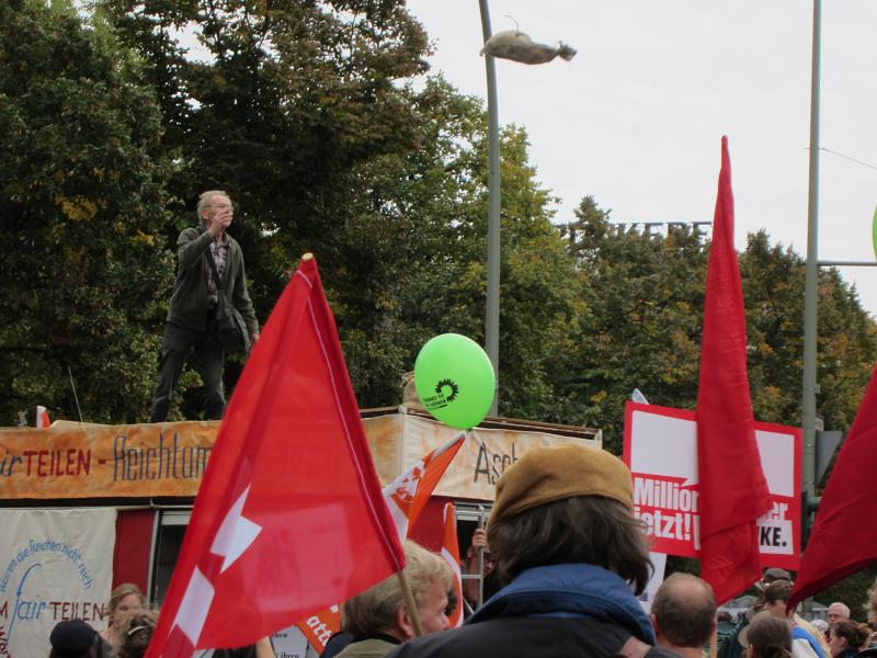 Demo Um-fair-teilen / Reichtum besteuern - Geldsack fliegt in die Menschenmenge